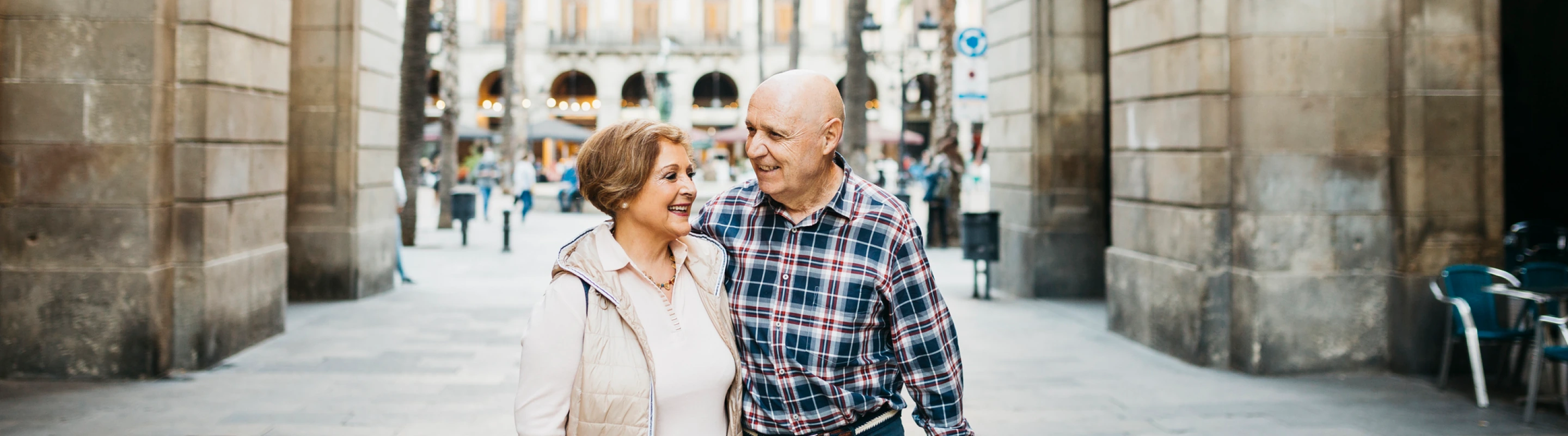 an older couple walking through a historic town with travel insurance for Spain