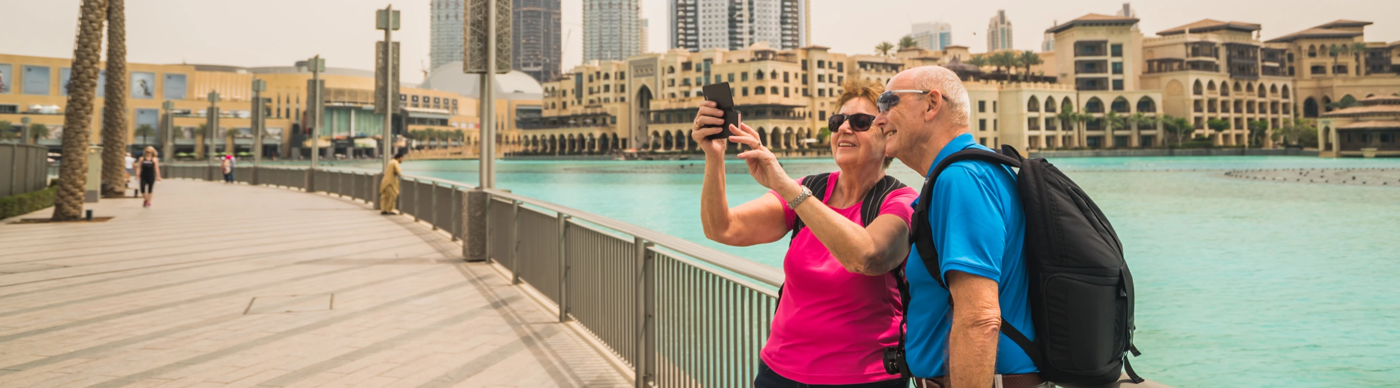 an older couple with travel insurance for the UAE pose and take a selfie in Souk al Bahar, Dubai