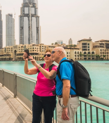 an older couple with travel insurance for the UAE pose and take a selfie in Souk al Bahar, Dubai