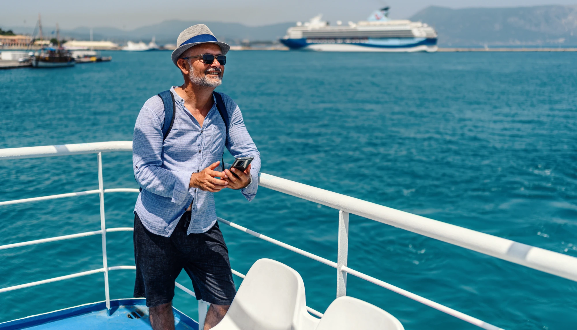 an older man leans on a railing near the ocean, enjoying his vacation after researching how to get the best deal on a cruise