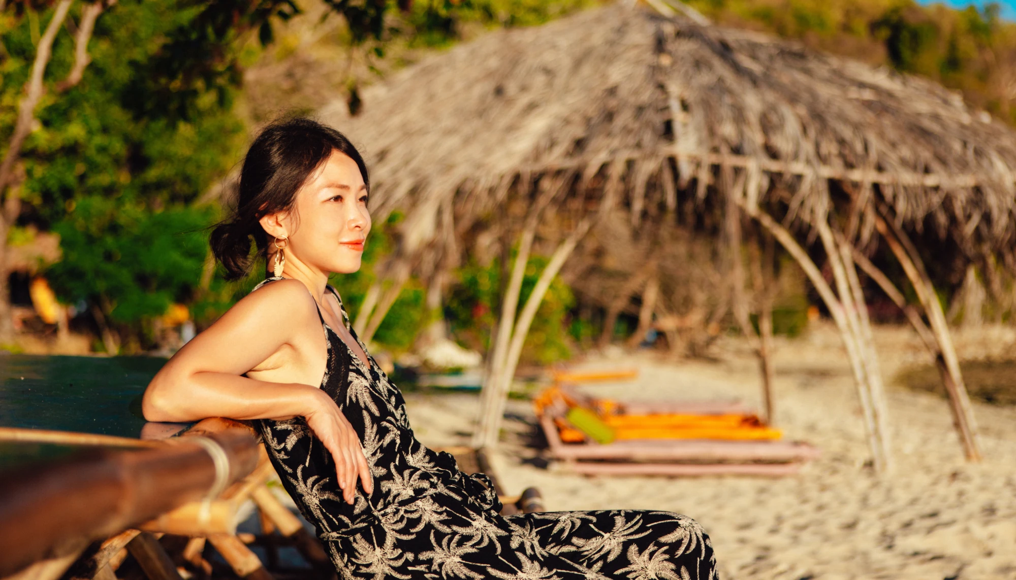 a Philipino woman relaxing on a beach in a black dress, visiting one of the best solo travel destinations 