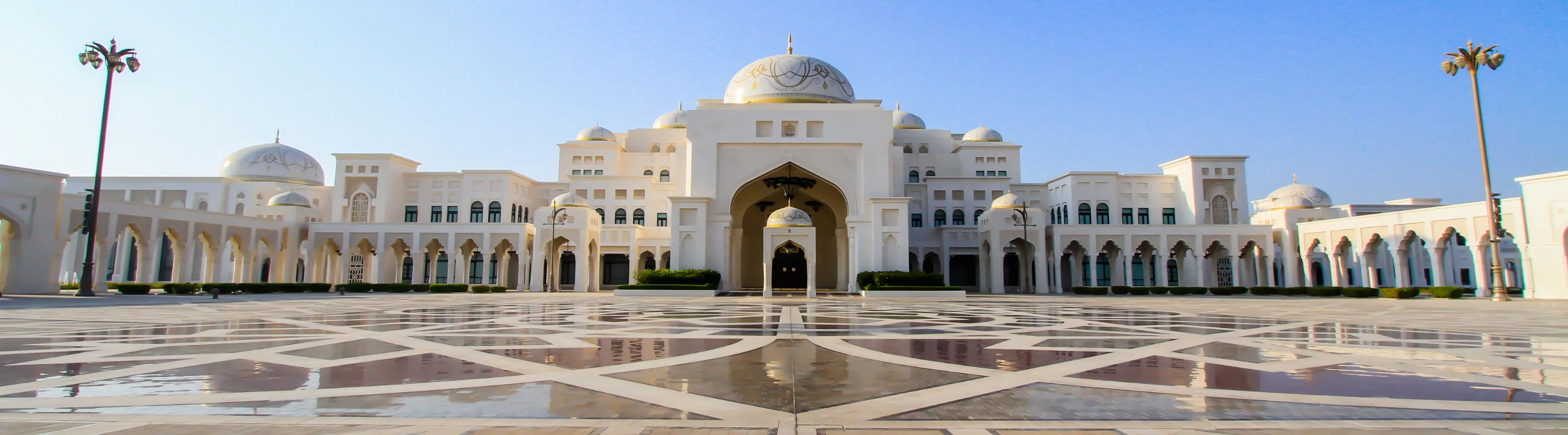 View of Qasr Al Watan palace and two palm trees on a clear day, highlighting travel insurance for Dubai trips