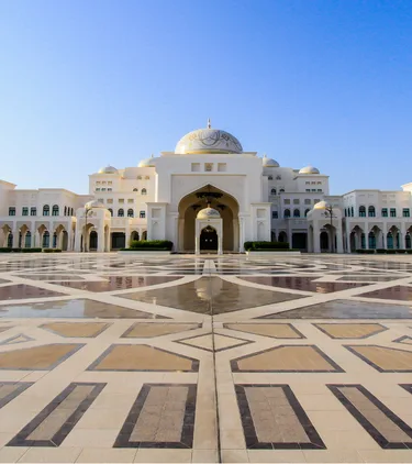 View of Qasr Al Watan palace and two palm trees on a clear day, highlighting travel insurance for Dubai trips