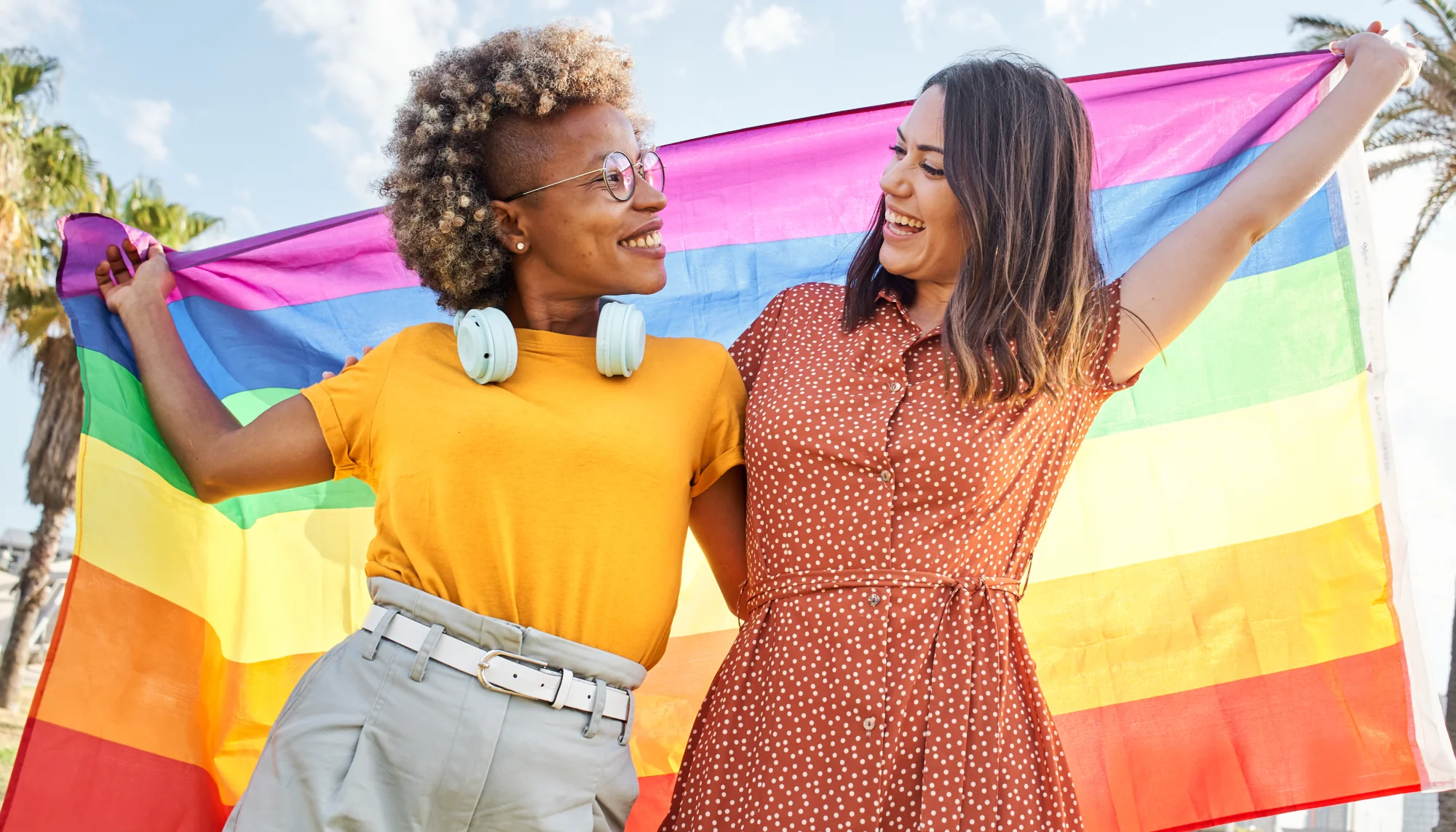 two queer individuals holding a rainbow flag and informing others about LGBTQ+ travel tips