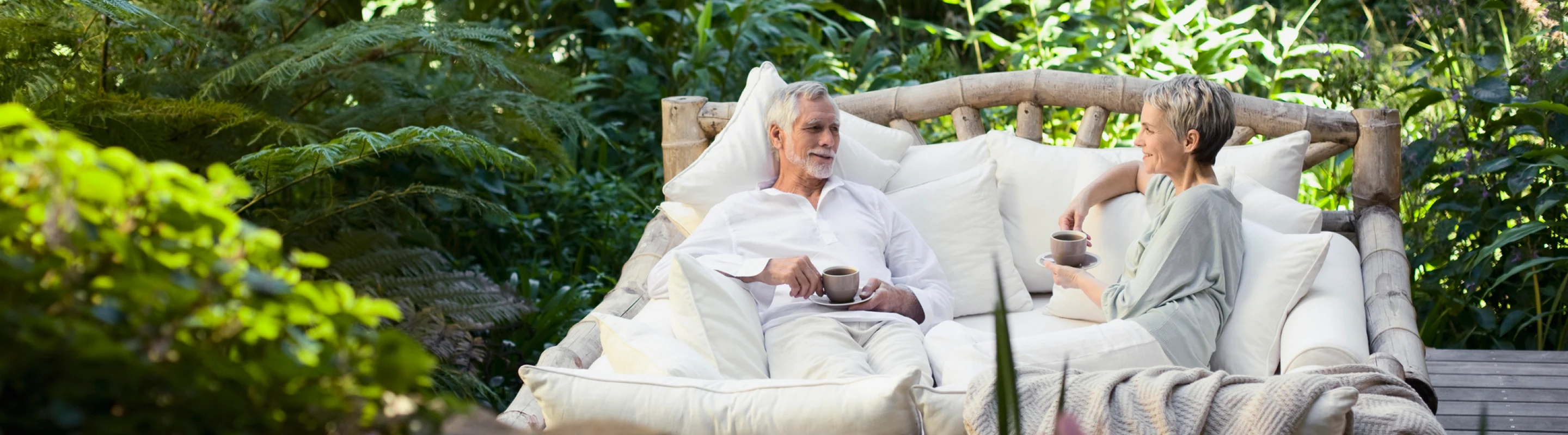 Senior couple with travel insurance plans sitting outside and having coffee and tea on vacation