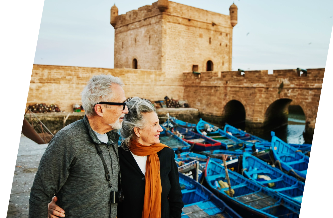 Senior couple walking past boats and historic architecture in Essaouira, Morocco