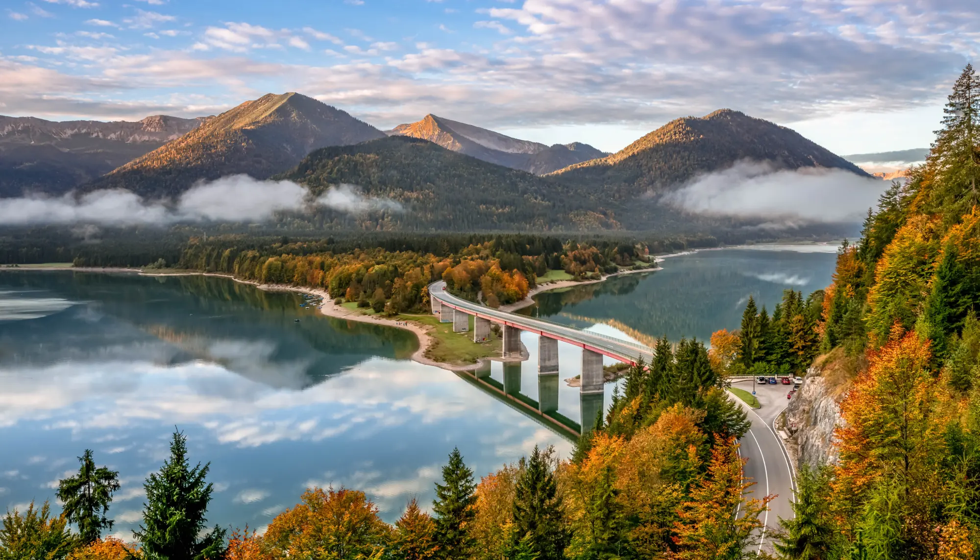 an aerial view of Sylvensteinsee and the Sylvenstein Bridge in the Bavarian Alps, highlighted in a Europe travel guide