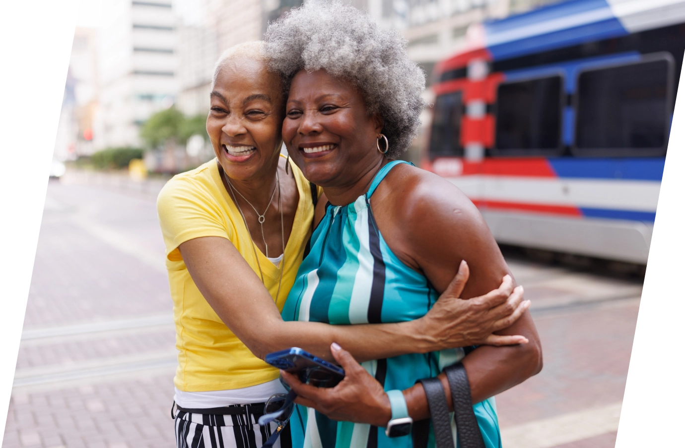 two older black women friends hug in a city setting on vacation, insured with travel insurance for Texas