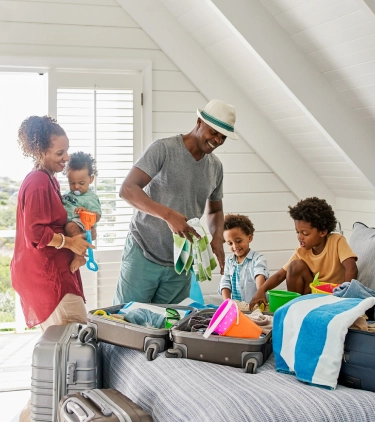 a mixed-race family of five with family travel insurance, unpacking and getting ready for a beach day at their vacation rental
