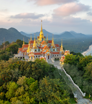 Aerial view of hilltop Wat Tang Sai temple with water and hills in the background highlighting travel insurance for Thailand