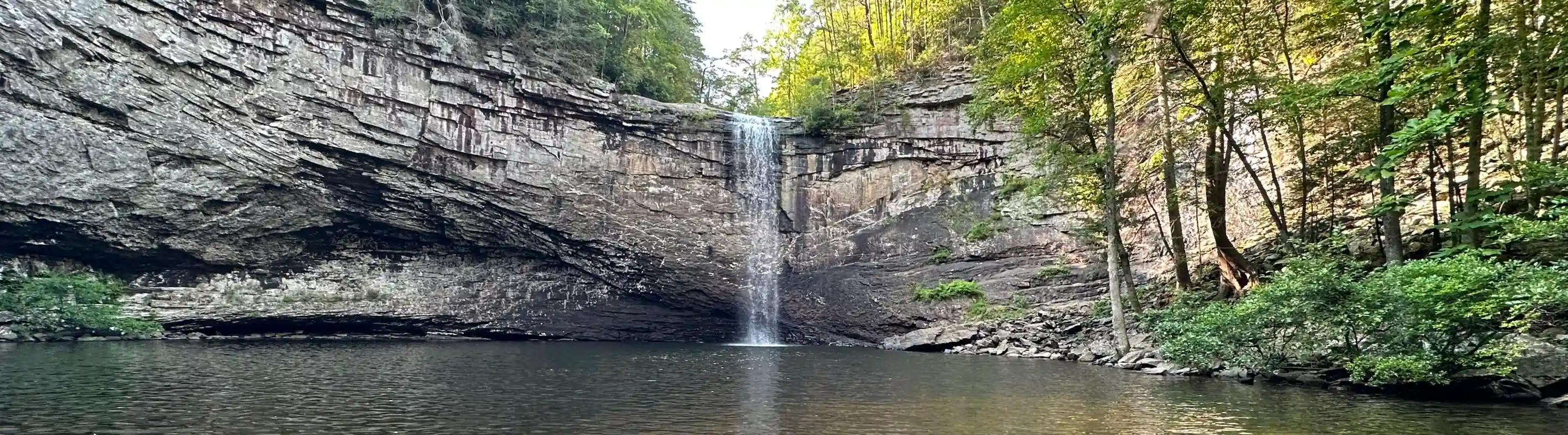 Waterfall flowing into the river in a forest in Sequatchie, highlighting travel insurance for Tennessee