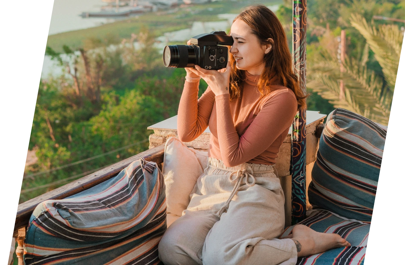 a young woman with brown hair and travel insurance for Egypt holds a camera up to her face to take pictures as she lounges