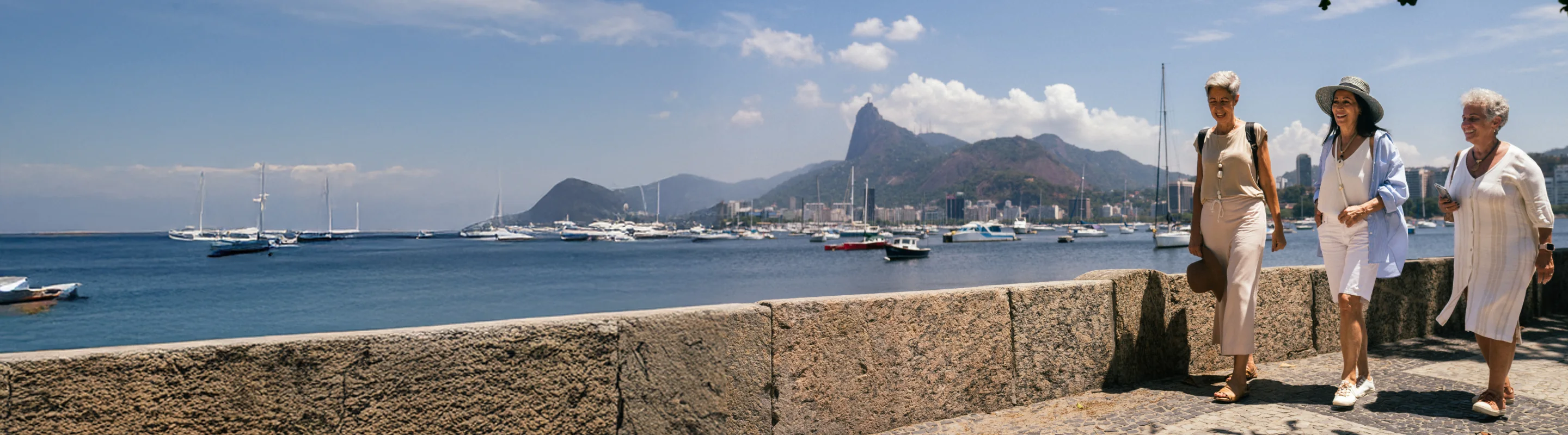 Three senior women with travel insurance for South America walking along the water in Brazil