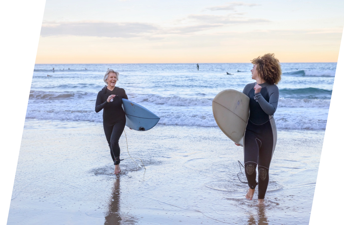 two women holding surfboards and running up the beach, insured with travel insurance for Australia 
