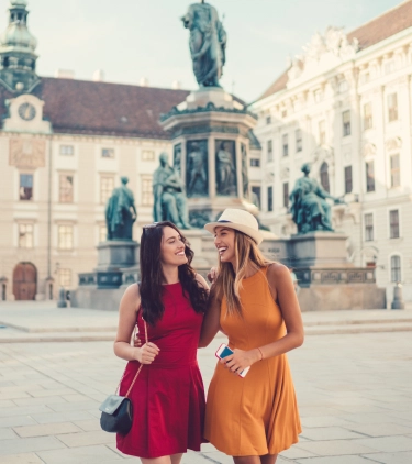 two women posing in front of the Maria Theresien Platz in Vienna, protected by travel insurance for Austria