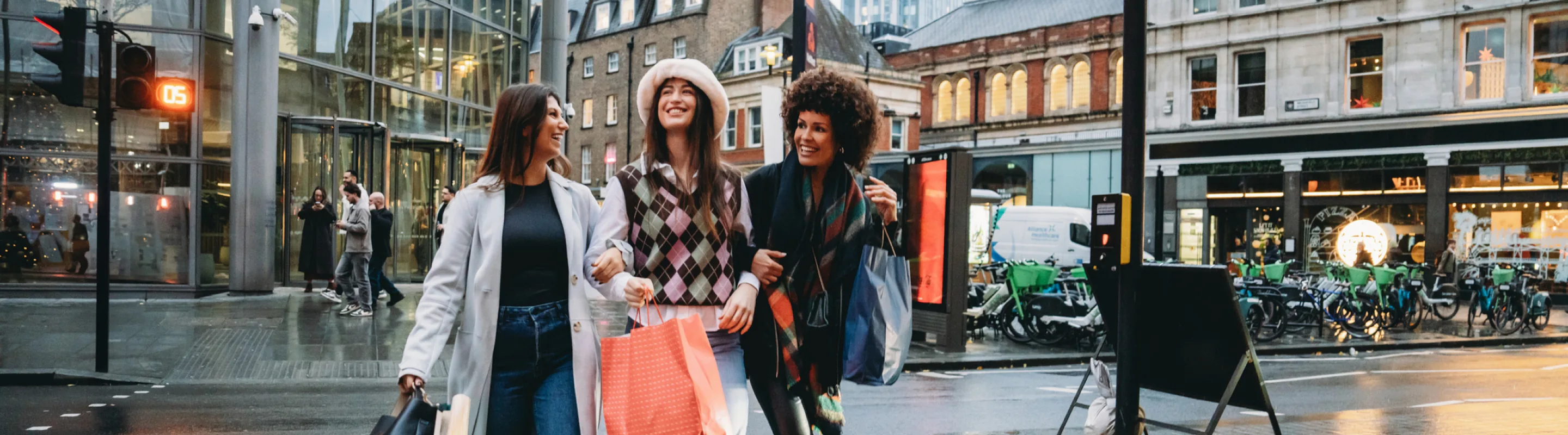 a group of women with travel insurance for the United Kingdom, carrying shopping bags as they walk through London