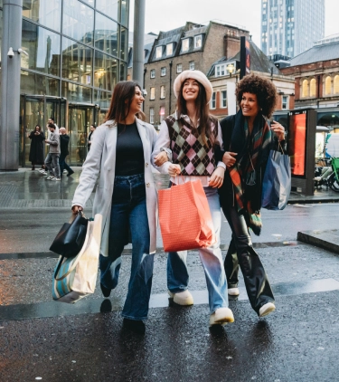 a group of women with travel insurance for the United Kingdom, carrying shopping bags as they walk through London