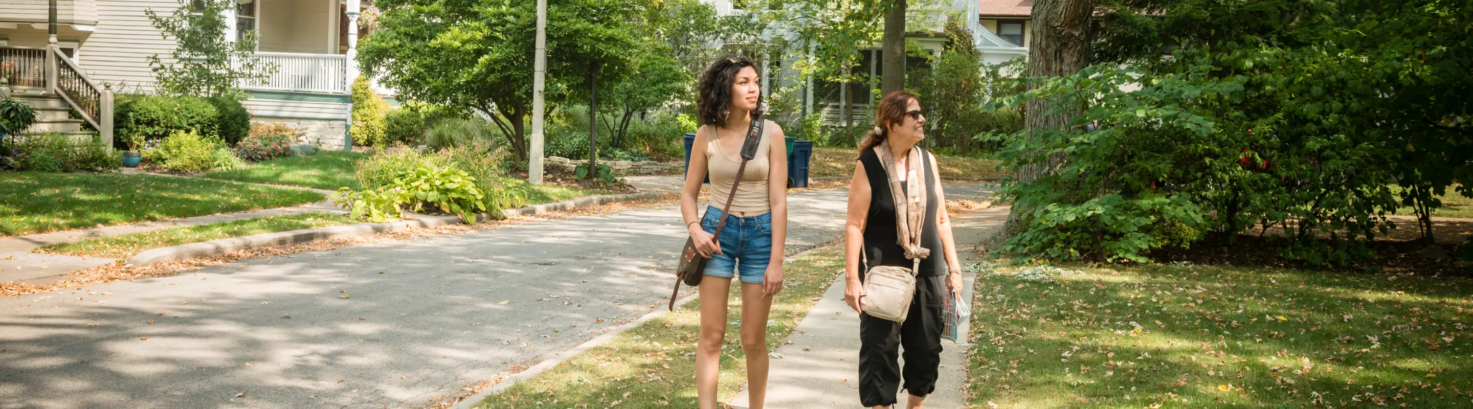 two women walk through a suburban neighborhood on vacation, insured with travel insurance for Illinois 