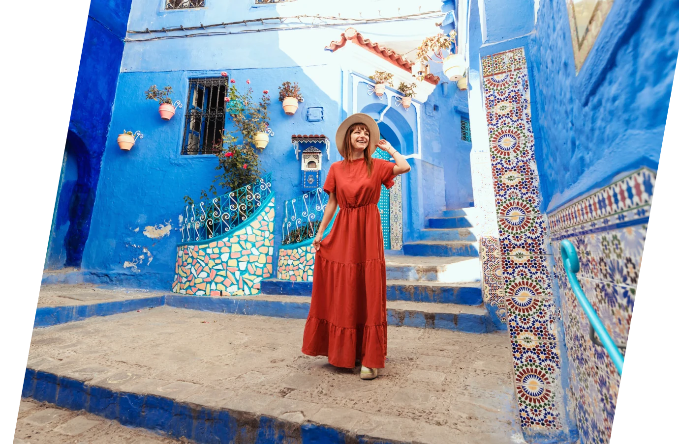 a young woman in a red dress poses in the blue city of Chefchaouen, insured with travel insurance for Morocco
