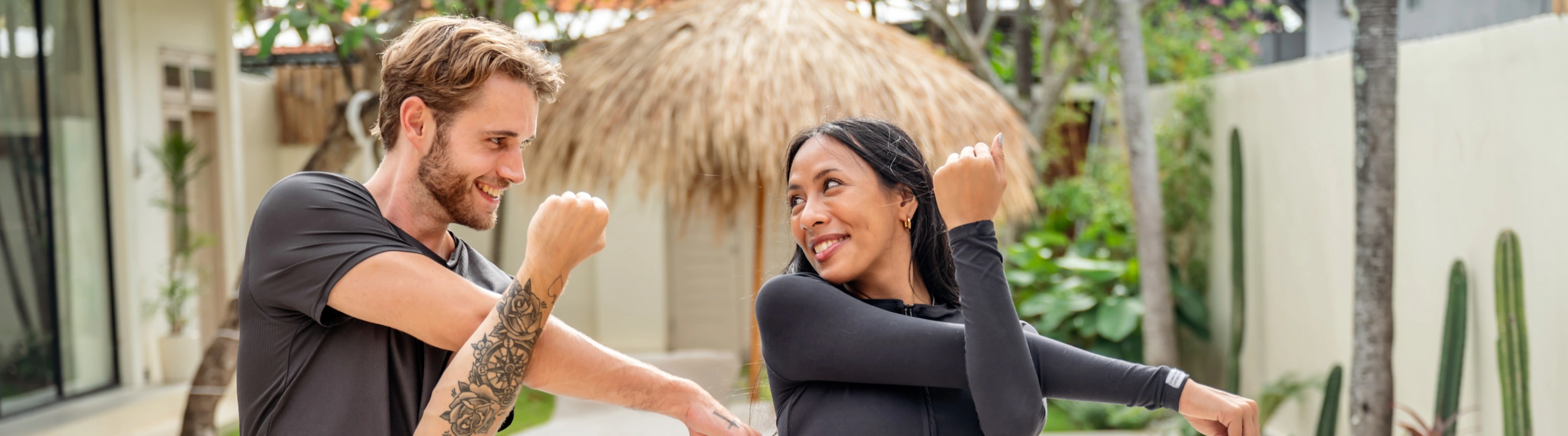 two young adults with travel insurance for wellness retreats take part in an outdoor stretching session 