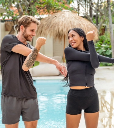 two young adults with travel insurance for wellness retreats take part in an outdoor stretching session 