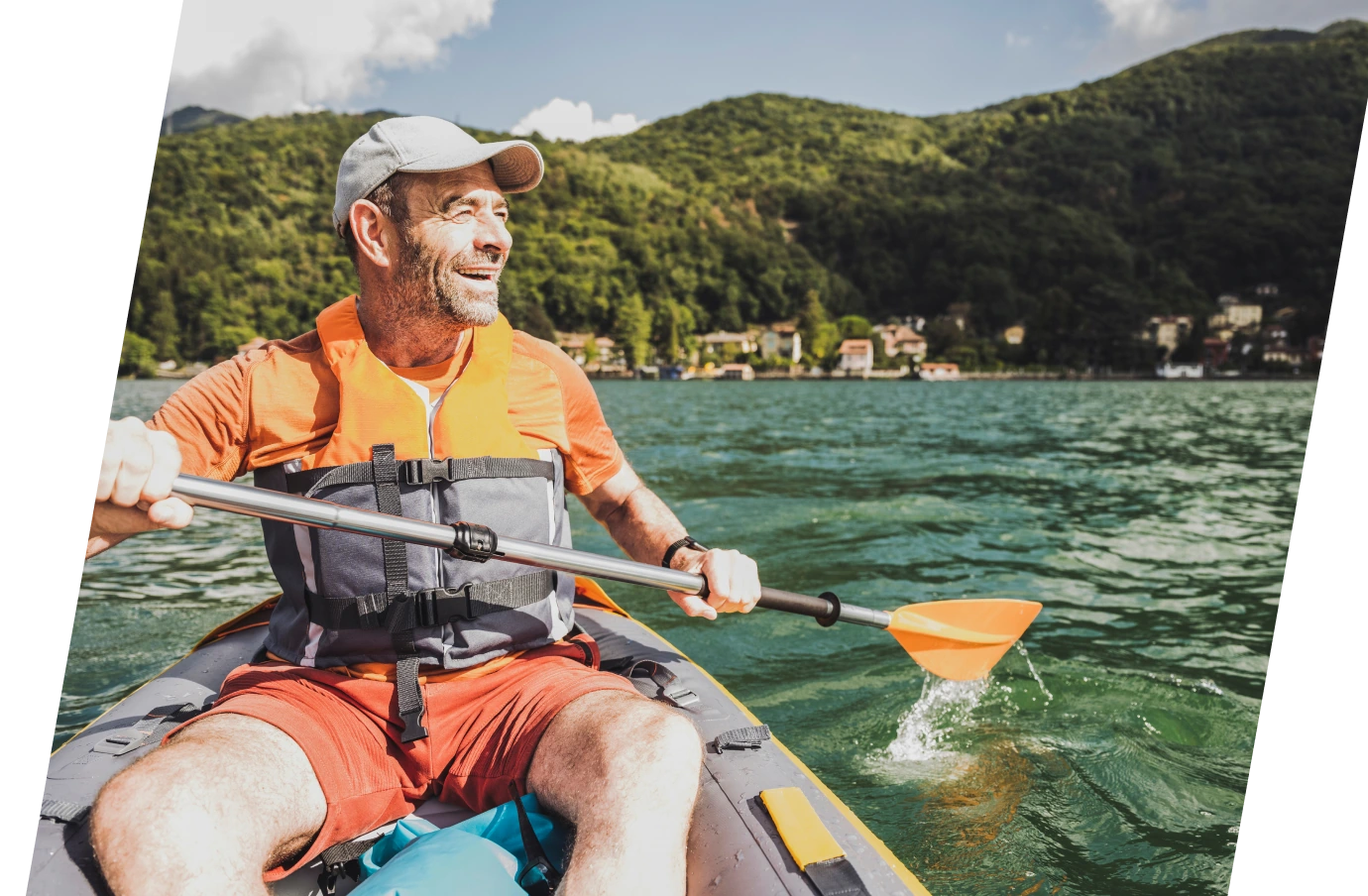 a middle-aged, solo man with travel insurance for wellness retreats kayaks on a mountain lake on a sunny day