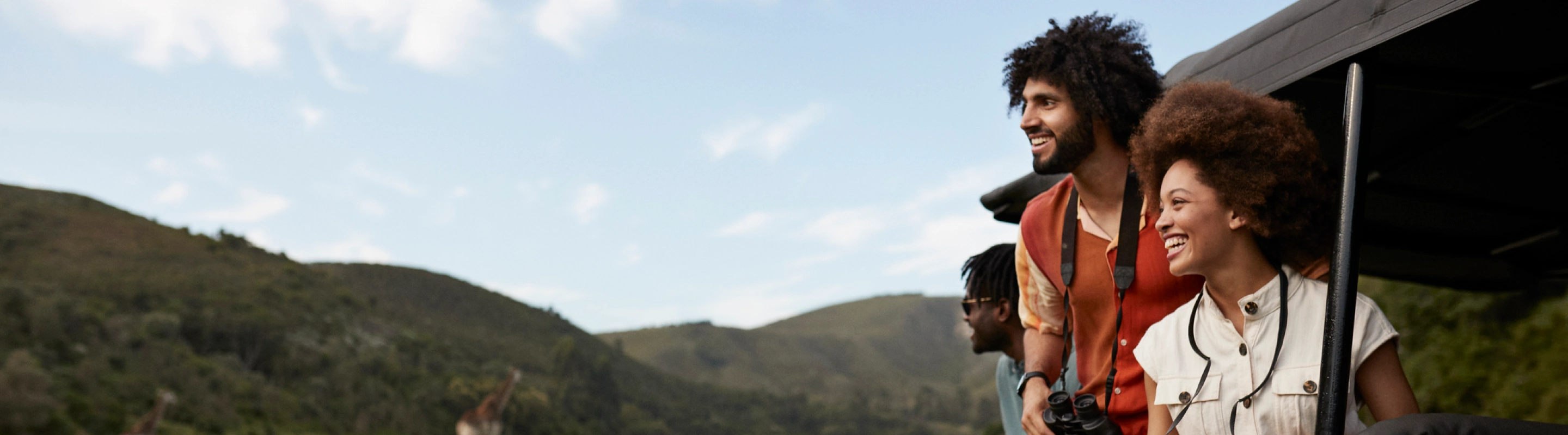 three mixed-race young adults with travel insurance for nature trips sightsee on a jeep safari in Africa 