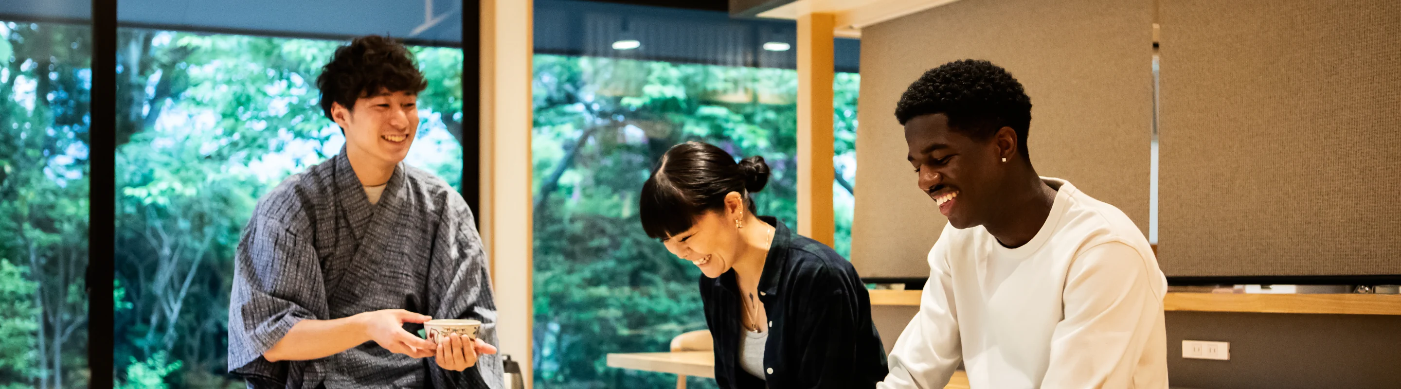 three young adults with travel insurance for wellness retreats smile as they partake in a traditional Japanese tea ceremony