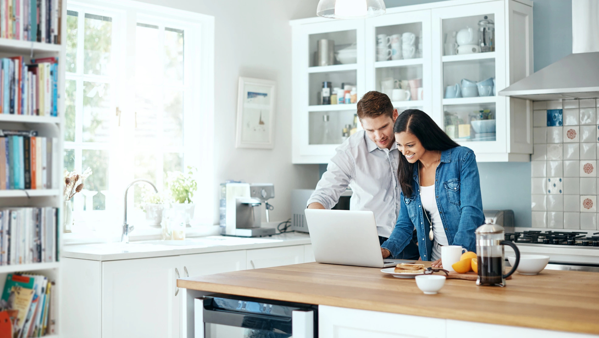 a couple using a laptop in their kitchen to calculate trip cost for their travel insurance policy