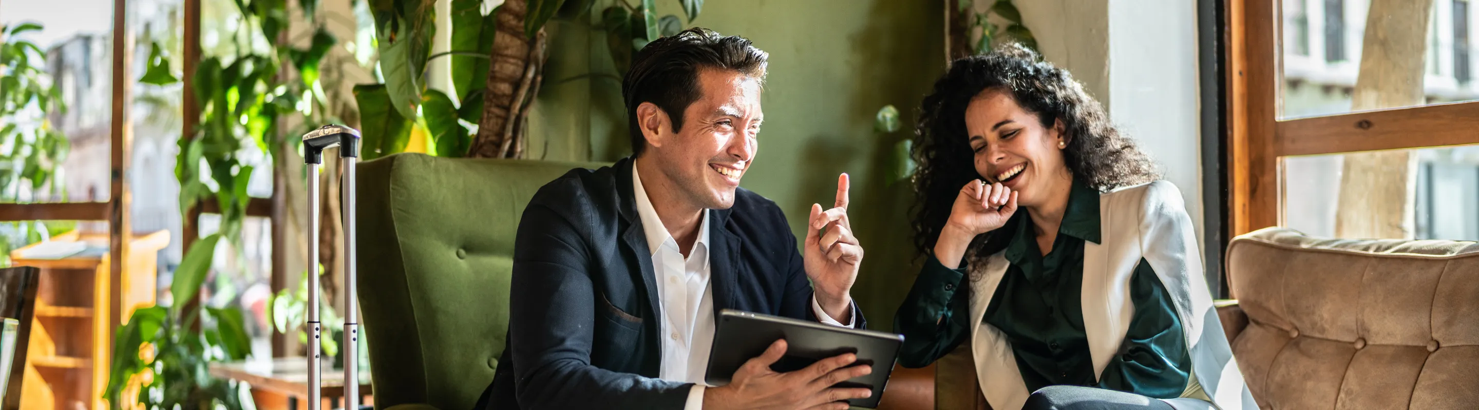 two colleagues work collaboratively in a hotel lounge, insured with business travel insurance 