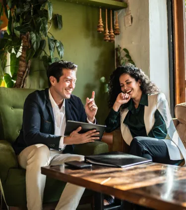 two colleagues work collaboratively in a hotel lounge, insured with business travel insurance 