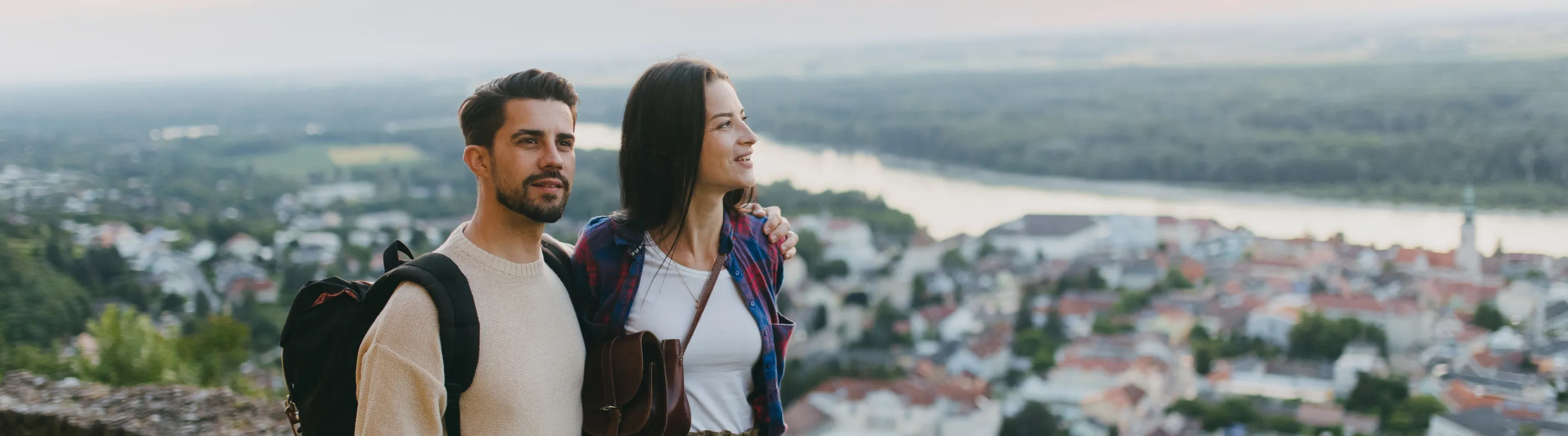 a couple with backpacker travel insurance explores a city viewpoint at sunset 