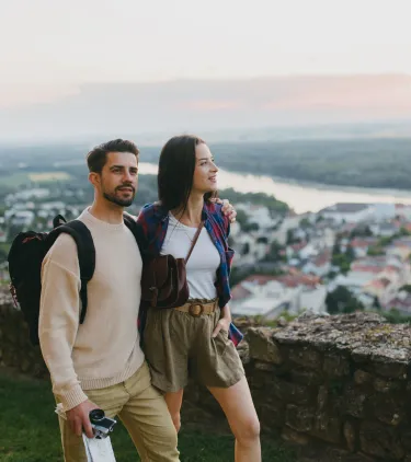 a couple with backpacker travel insurance explores a city viewpoint at sunset 