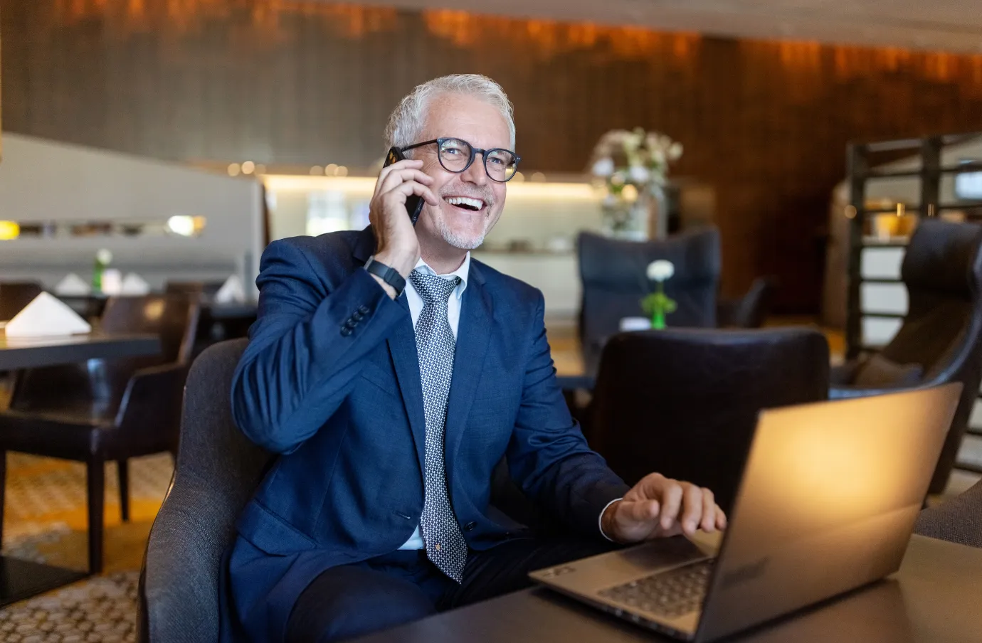 an older professional takes a call during his business trip, insured with business travel insurance 