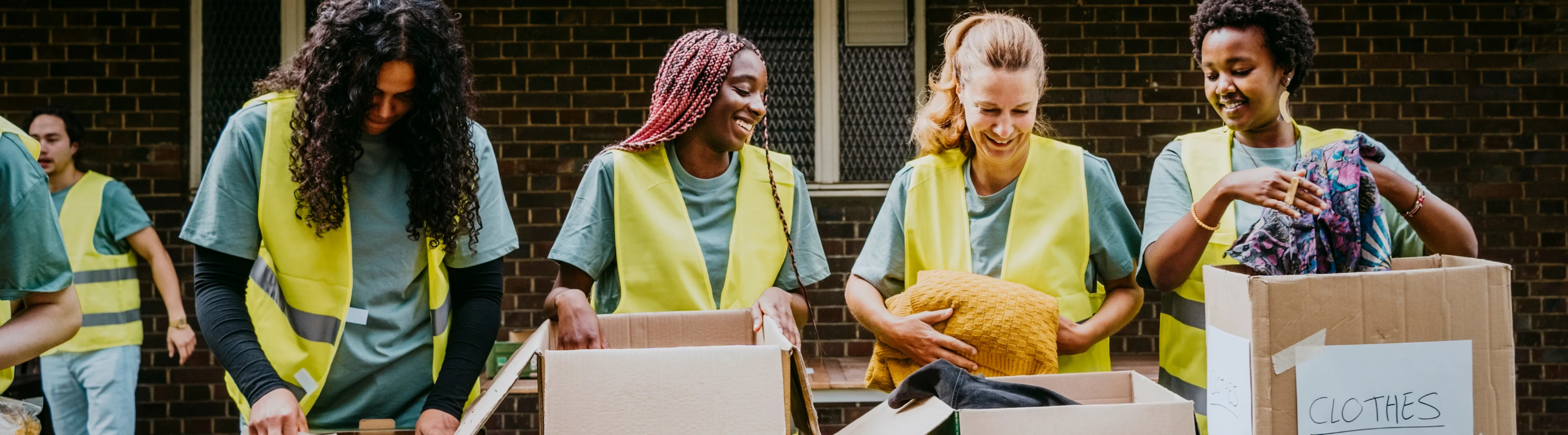 four volunteers sort clothing donations together on their service trip, insured with volunteer travel insurance 