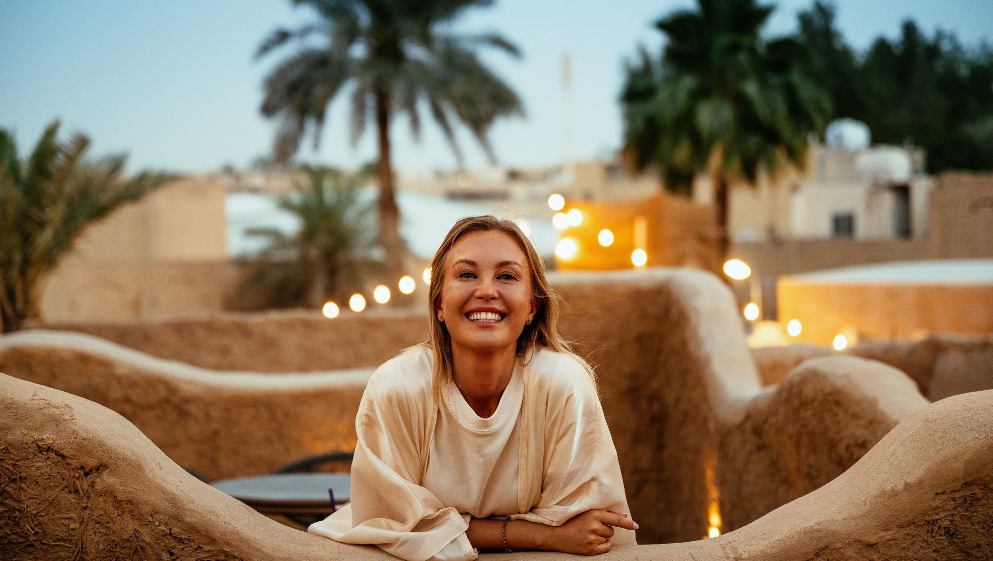 a young woman smiles in a desert in the Middle East, after researching "Does travel insurance cover wars and terrorism?"