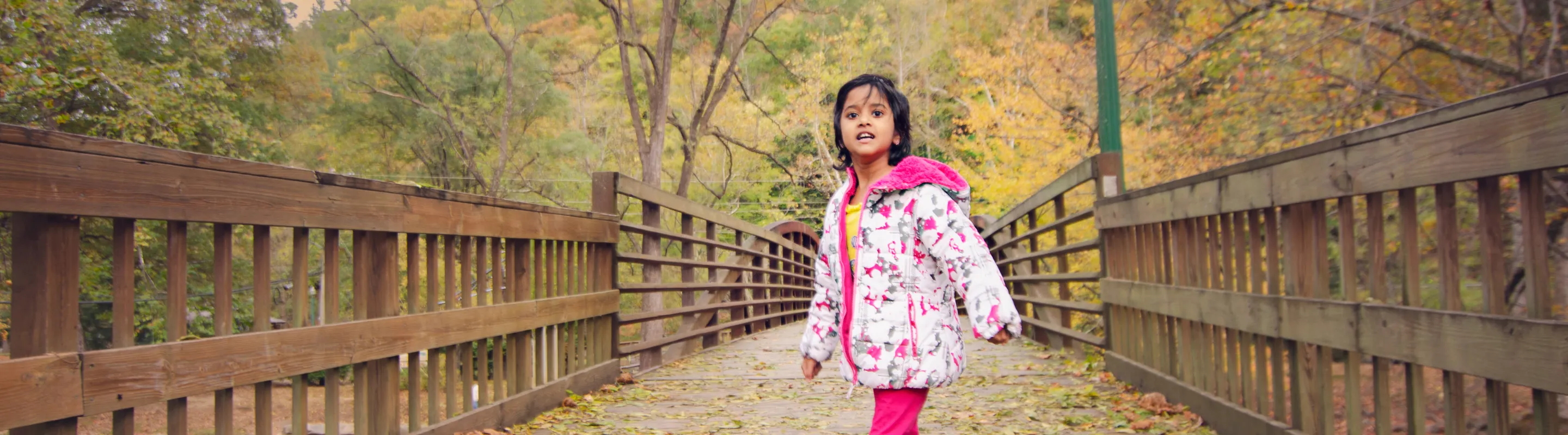 a young girl stands on a bridge in the Great Smoky Mountains in Autumn, insured with travel insurance for Tennessee 