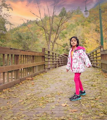 a young girl stands on a bridge in the Great Smoky Mountains in Autumn, insured with travel insurance for Tennessee 