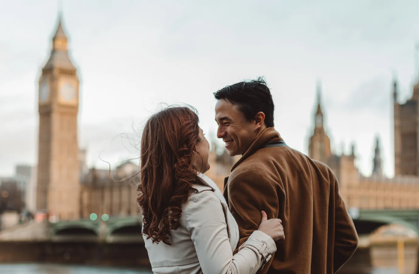 a couple with travel insurance for the UK embraces in front of Big Ben and Westminster in central London