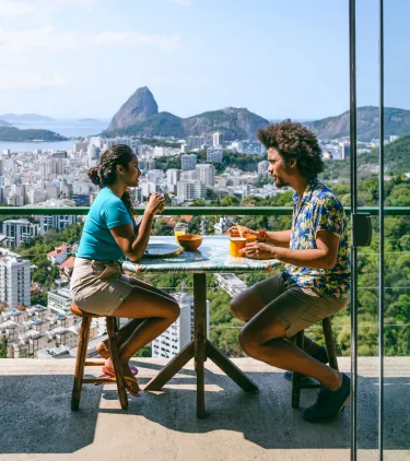 a young couple with travel insurance for South America dines at a restaurant overlooking Rio de Janeiro, Brazil
