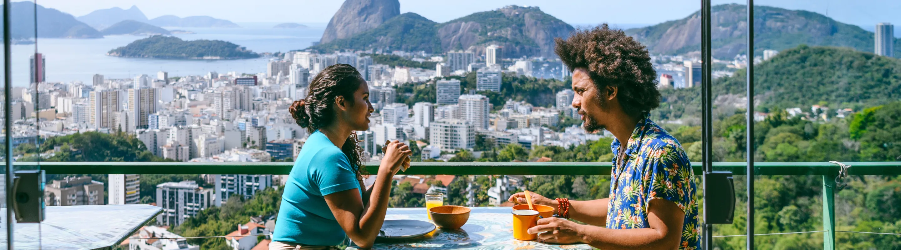 a young couple with travel insurance for South America dines at a restaurant overlooking Rio de Janeiro, Brazil