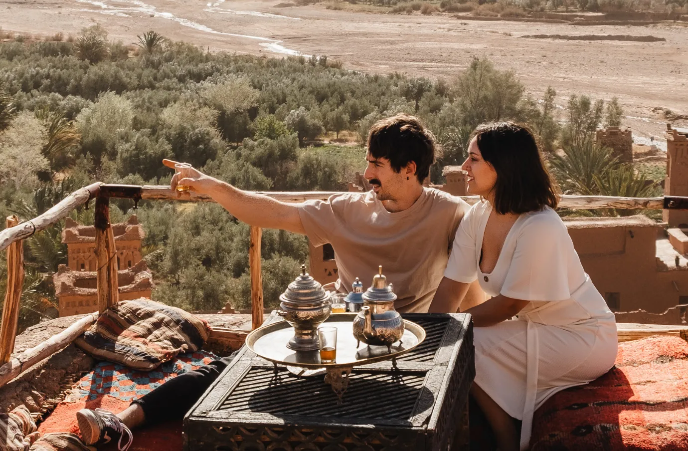 a young couple drinks tea in a Moroccan desert oasis, insured with travel insurance for Morocco