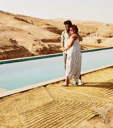 Couple walking along a pool in the desert with travel insurance for their all-inclusive vacation