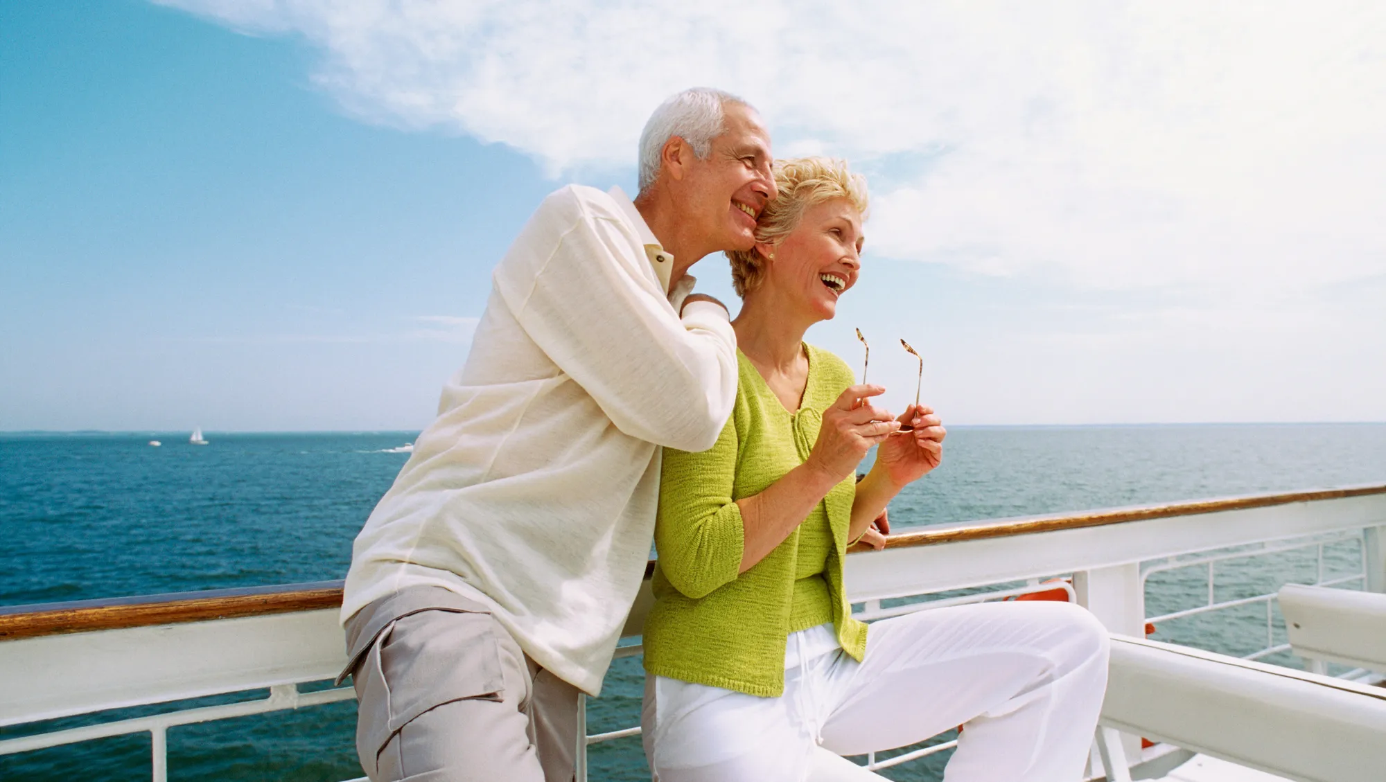 a senior couple leans against a cruise ship railing on vacation after reading our cruise myths guide 