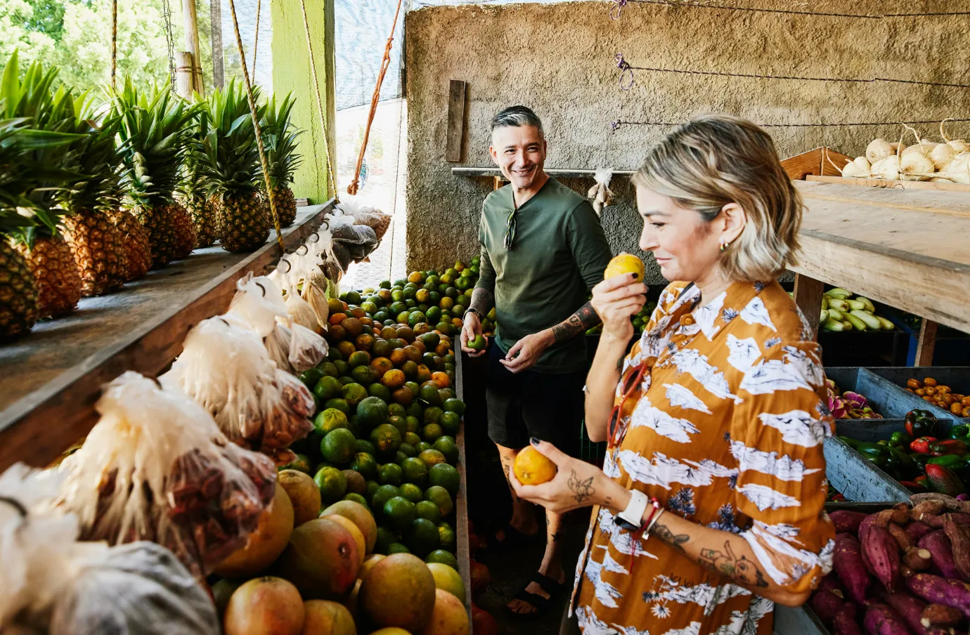 a middle-aged couple shops for local produce at a Mexican market, insured with travel insurance for Mexico