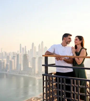 a couple with travel insurance for Dubai stand on a high-rise observation deck overlooking Dubai
