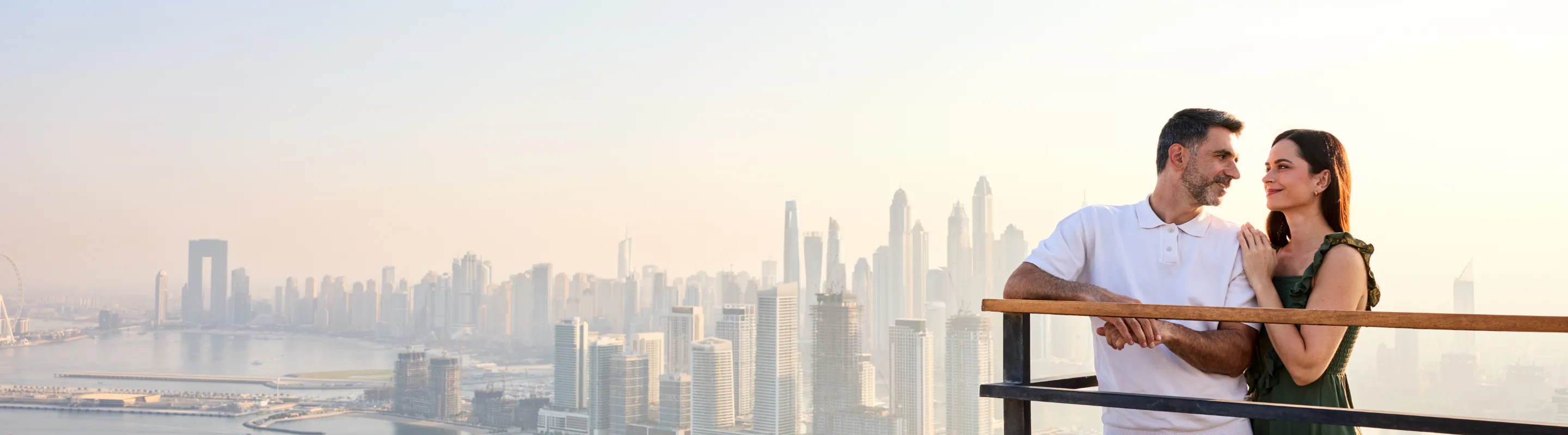 a couple with travel insurance for Dubai stand on a high-rise observation deck overlooking Dubai