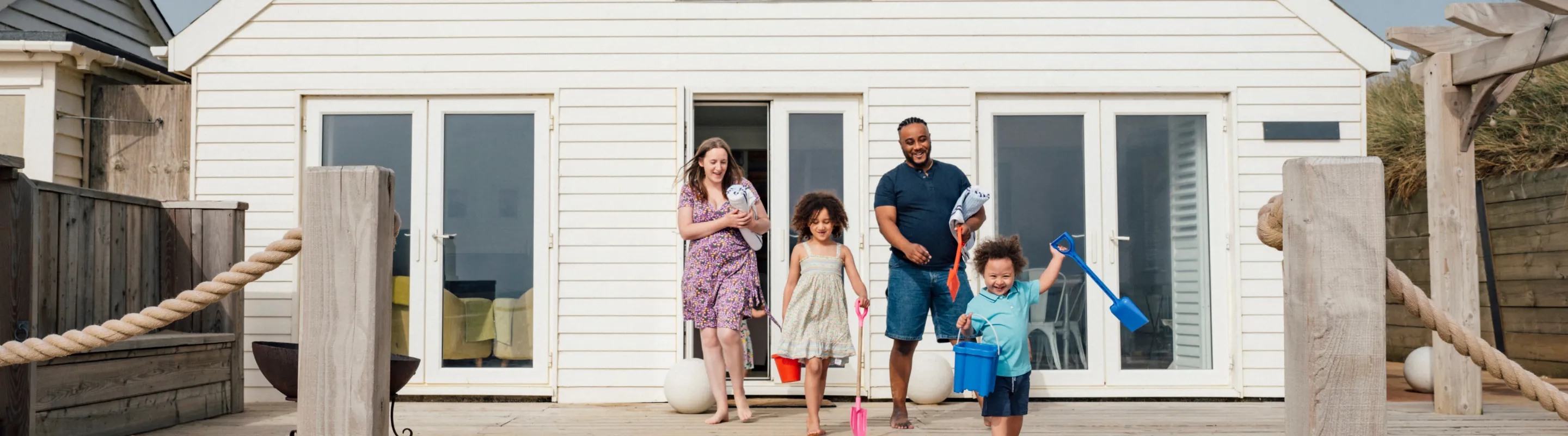 Parents with vacation rental travel insurance heading to the beach with their two young children from the back patio