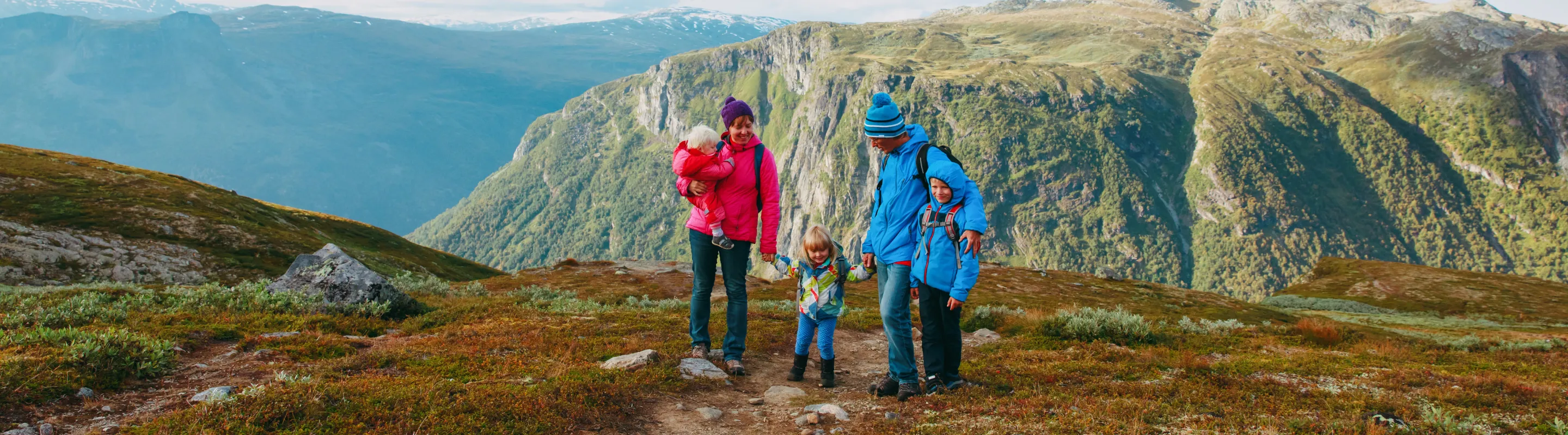 Parents with travel insurance for Europe hiking with their three children in the mountains in Norway