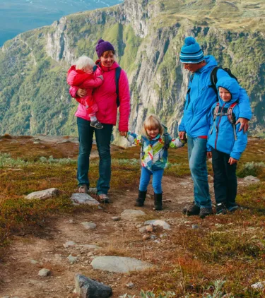 Parents with travel insurance for Europe hiking with their three children in the mountains in Norway